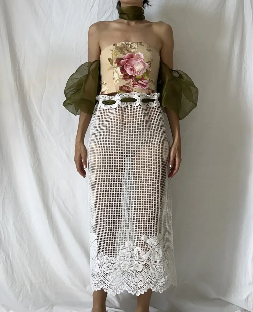 Strapless bustier in vintage floral upholstery fabric with olive organza sleeves, over a white crochet-lace midi skirt.
