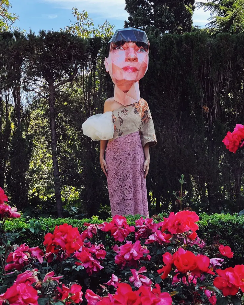 Cloud sleeve tapestry net maxi dress with a Big Head paper mask in Montjuic Barcelona