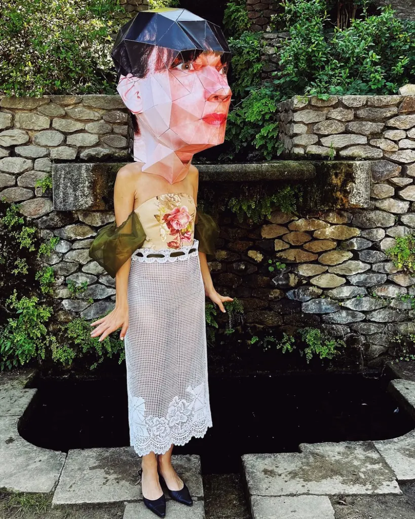 Vintage bustier tapestry dress with curtain skirt and bouffant sheer sleeves with Big Head paper mask in Montjuic Barcelona
